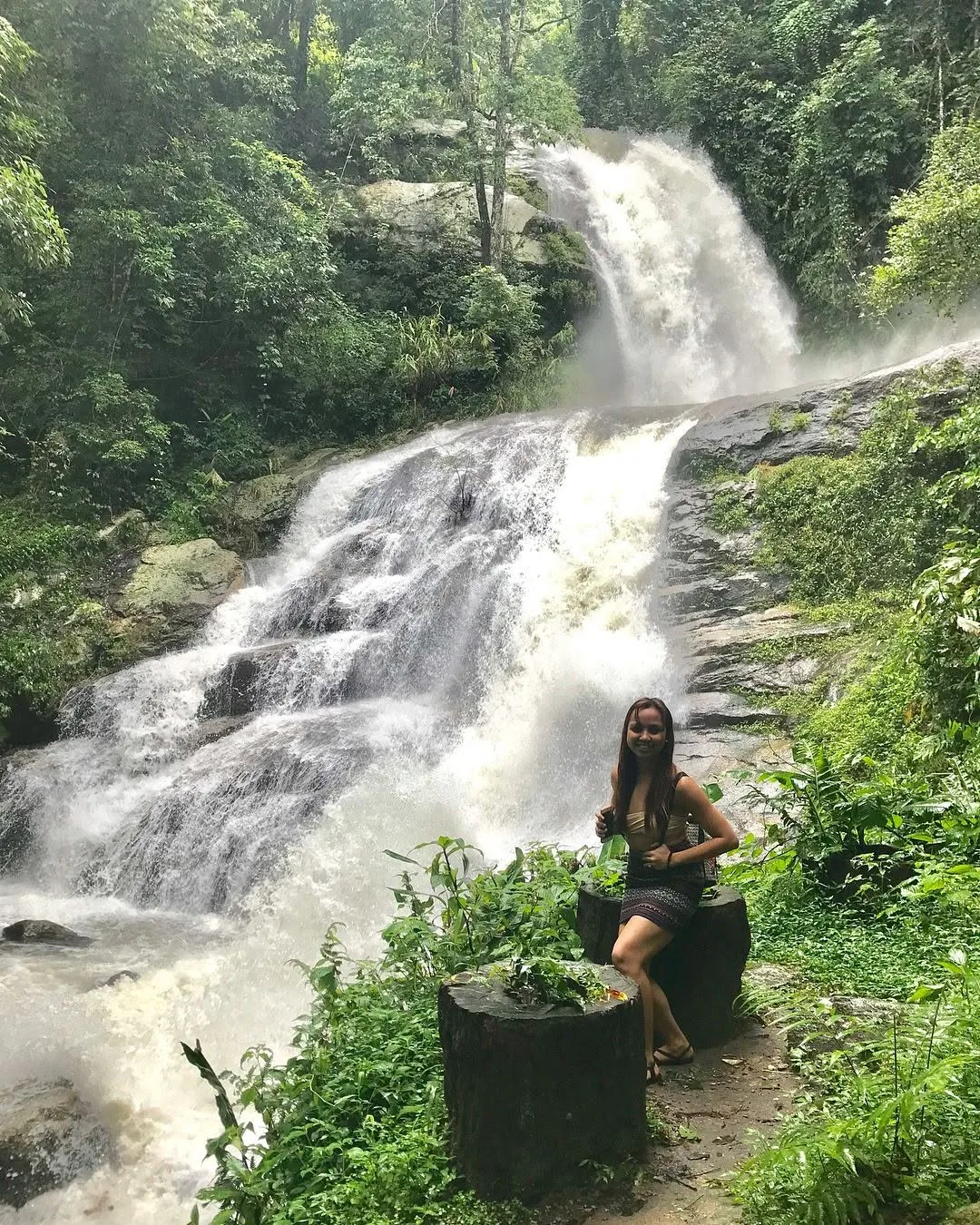 Dee standing beside a wide, rushing waterfall