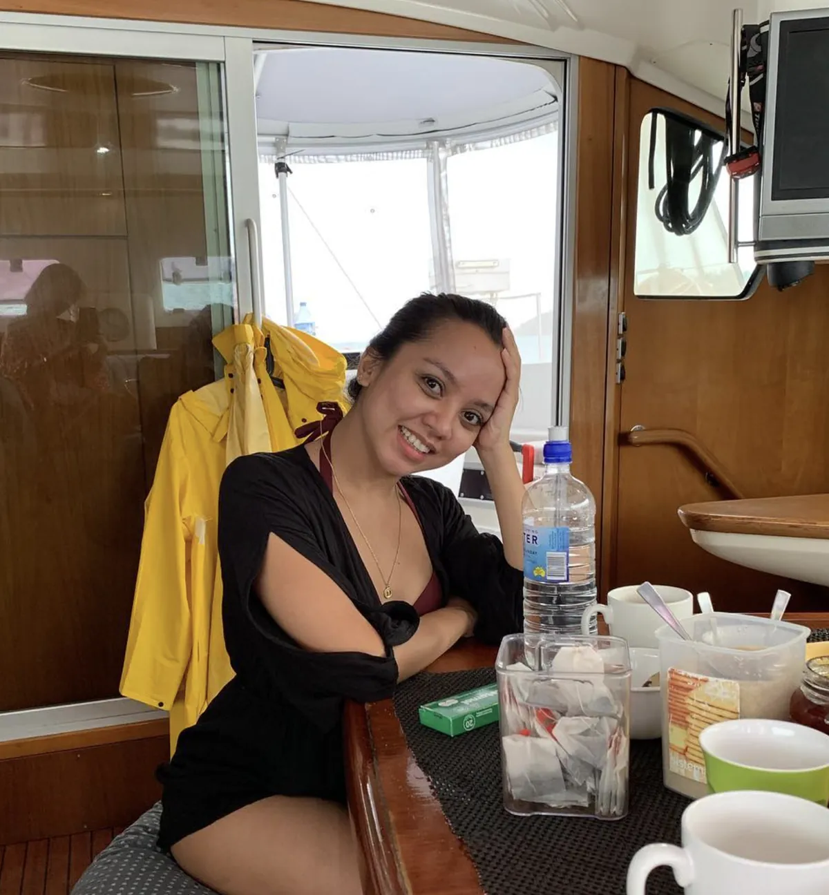Dee smiling at a table inside the boat cabin