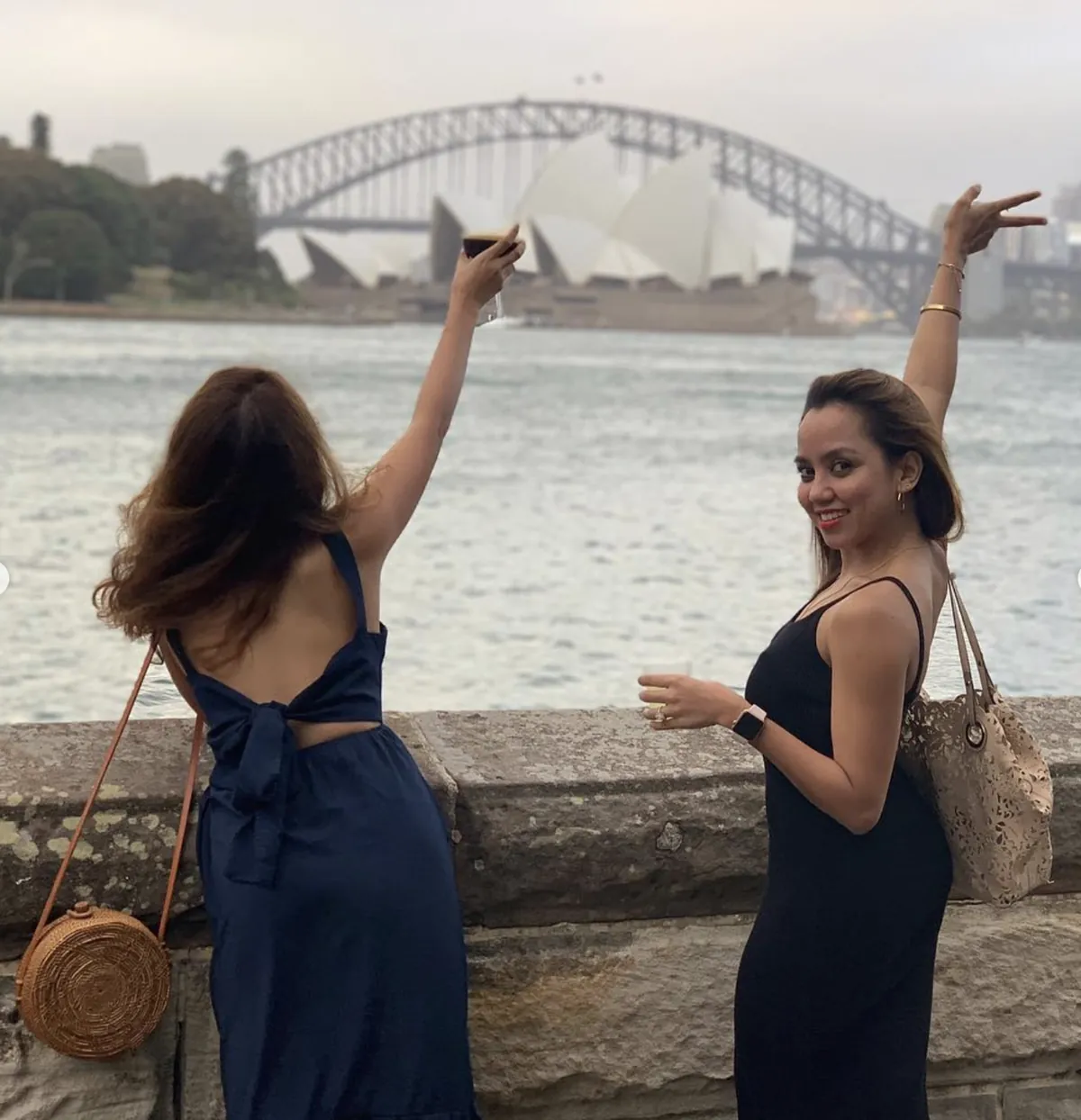 Two friends raising their arms toward the Opera House