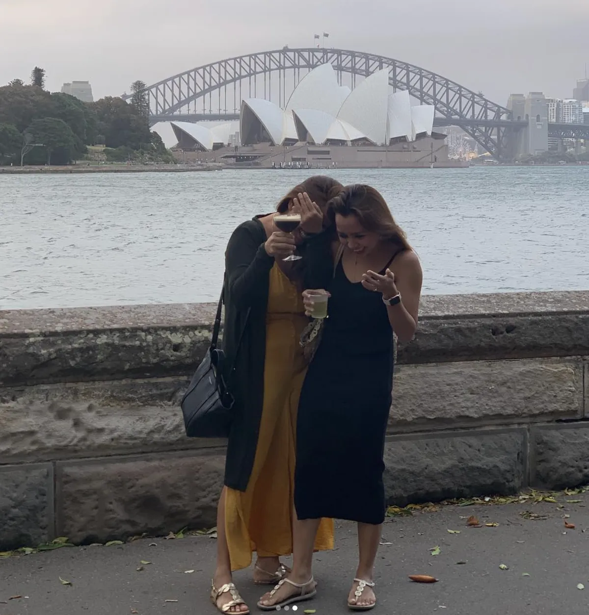 Two friends doubled over laughing by the harbour