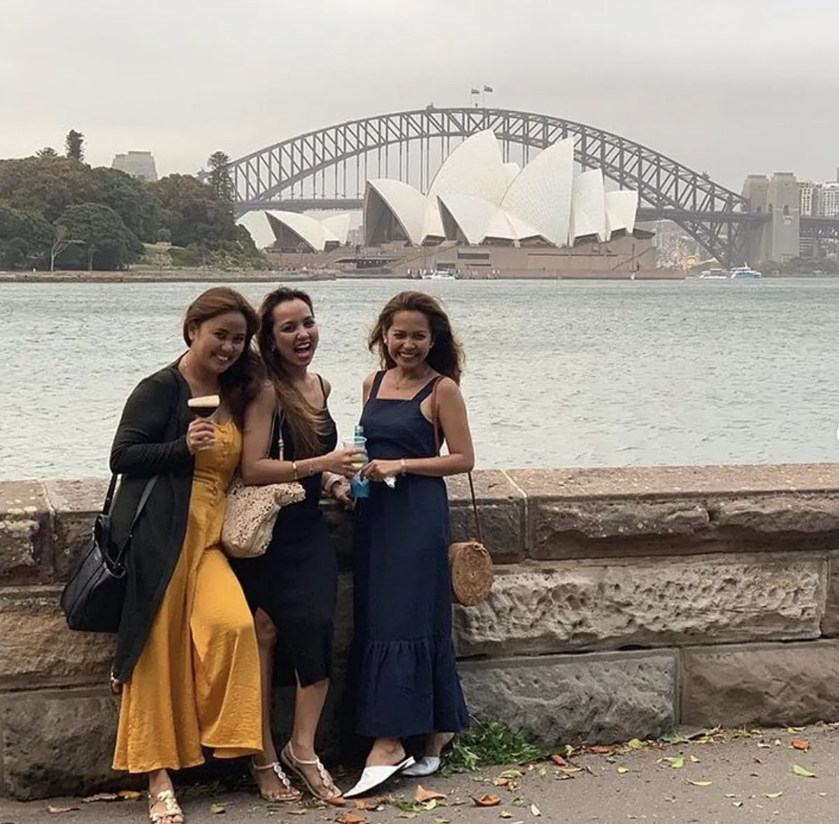 Dee and two friends laughing in front of the Sydney Opera House and Harbour Bridge