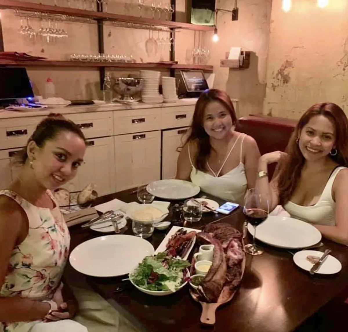 Dee and two friends at a dinner table with a tomahawk steak at Chophouse Sydney