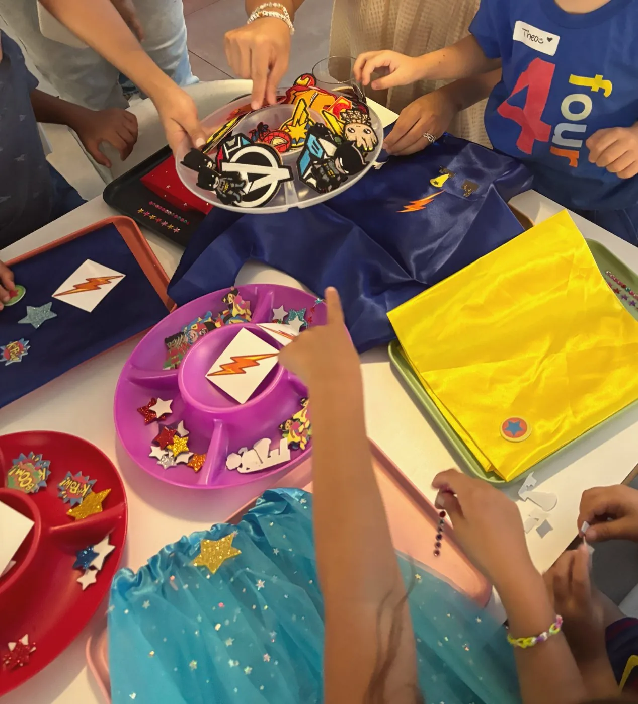 Children decorating capes at the craft table, the birthday boy in his 'four' t-shirt