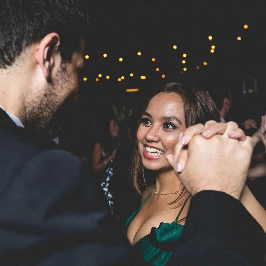 Dee smiling as she dances with her husband under string lights