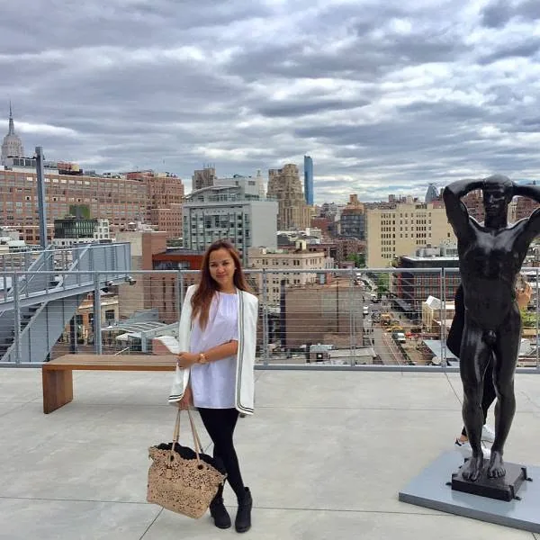 Dee on a rooftop terrace beside a bronze sculpture