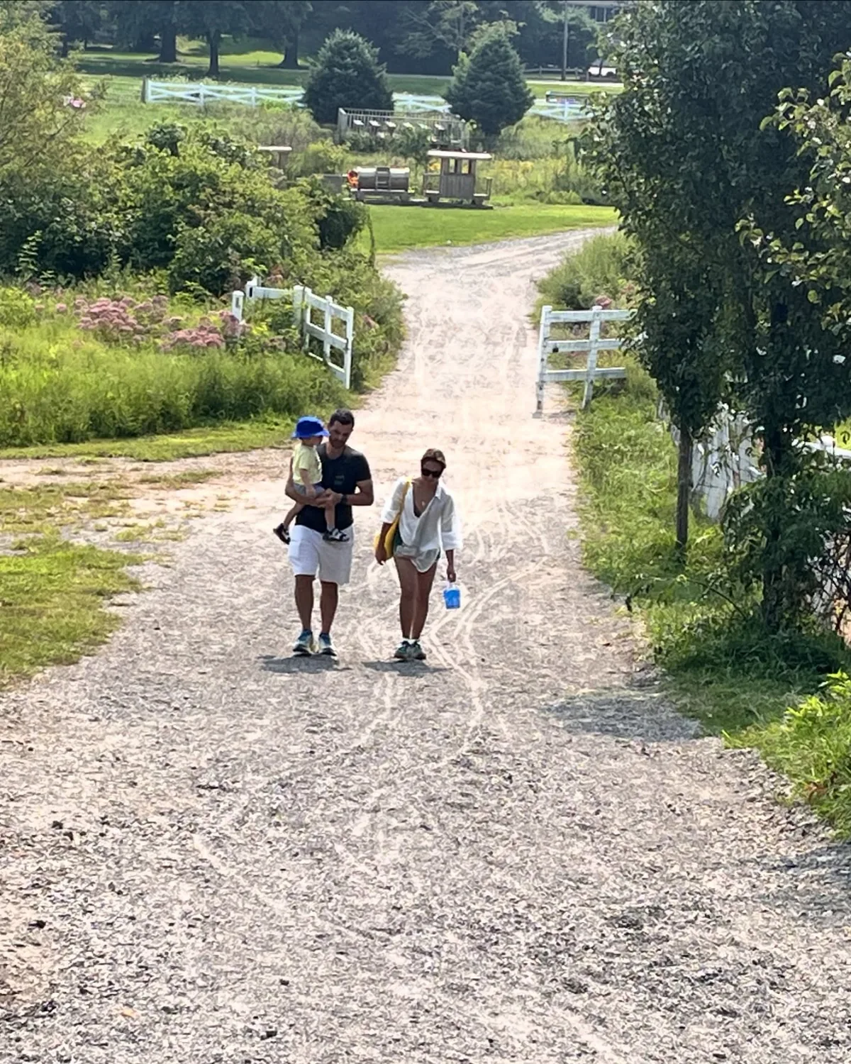 Dee and her husband, carrying their toddler, walking down a gravel path
