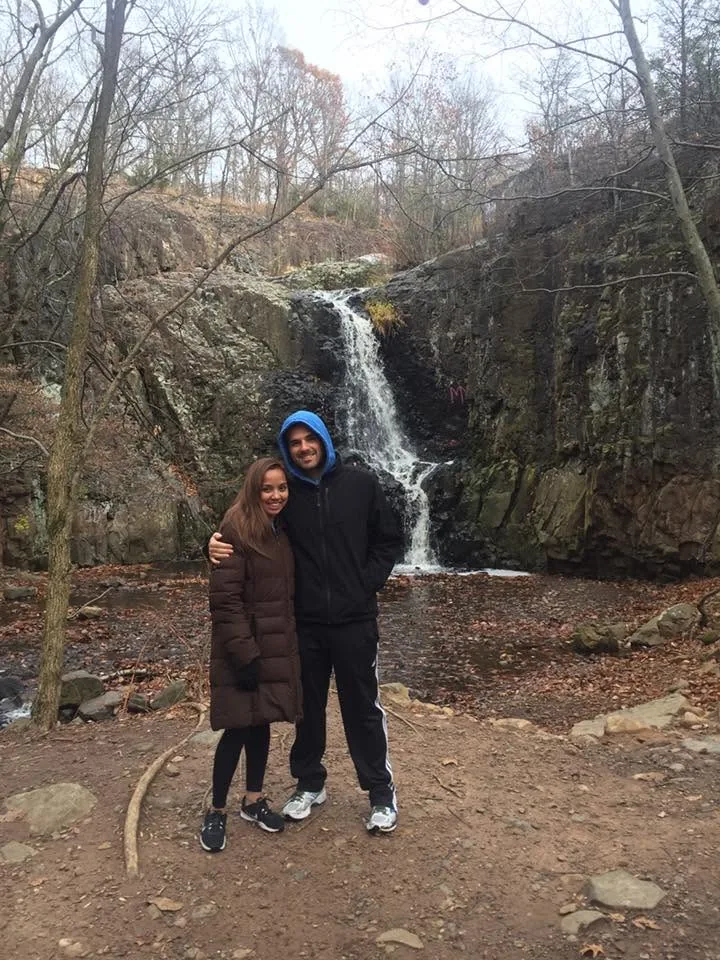 Dee and her husband in winter coats in front of a waterfall