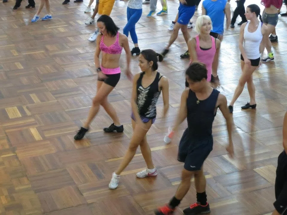 Dancers in training clothes practising steps together on a parquet floor