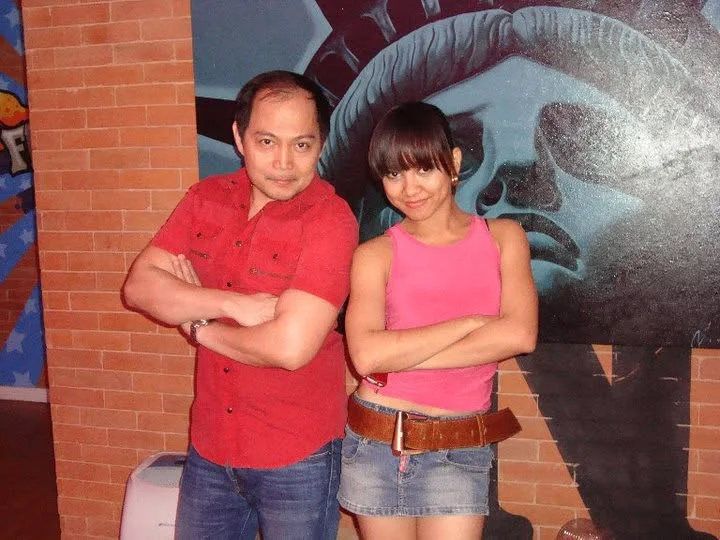 Dee and her Pilates and Gyrotonic coach posing with arms crossed in front of a mural