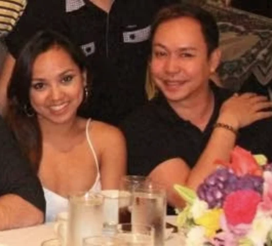 Dee smiling at a dinner table beside her Philippine dancesport coach Bong Marquez