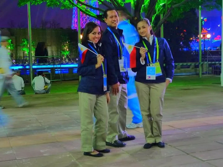 Dee with her gymnastics coach and a teammate in Team Philippines uniforms holding small flags